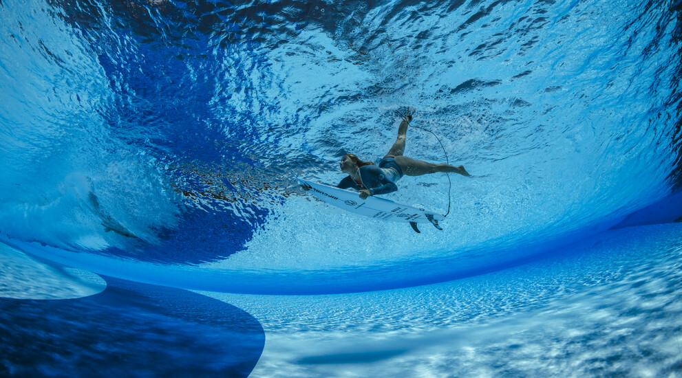 Im derzeit gr&ouml;&szlig;ten Wellenpark Europas kannst du das ganze Jahr &uuml;ber surfen. Das Bild zeigt eine Surferin beim Duckdive unter eine k&uuml;nstlichen Welle hindurch.